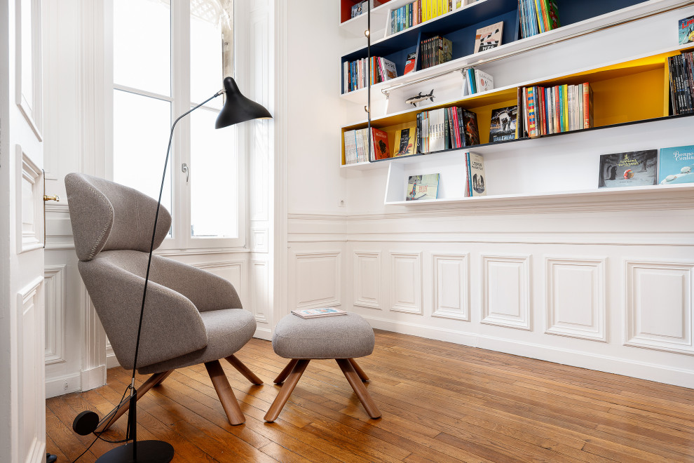 Mittelgroßes Modernes Lesezimmer mit weißer Wandfarbe, braunem Holzboden, Kamin, Kaminumrandung aus Holz, freistehendem Schreibtisch, braunem Boden, Tapetendecke und vertäfelten Wänden in Bordeaux