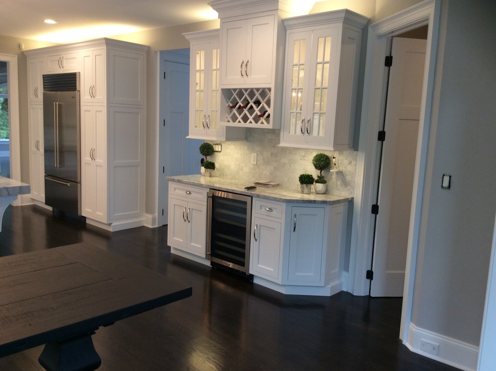 Photo of a small transitional single-wall wet bar in New York with beaded inset cabinets, white cabinets, grey splashback, marble splashback, dark hardwood floors, brown floor and marble benchtops.