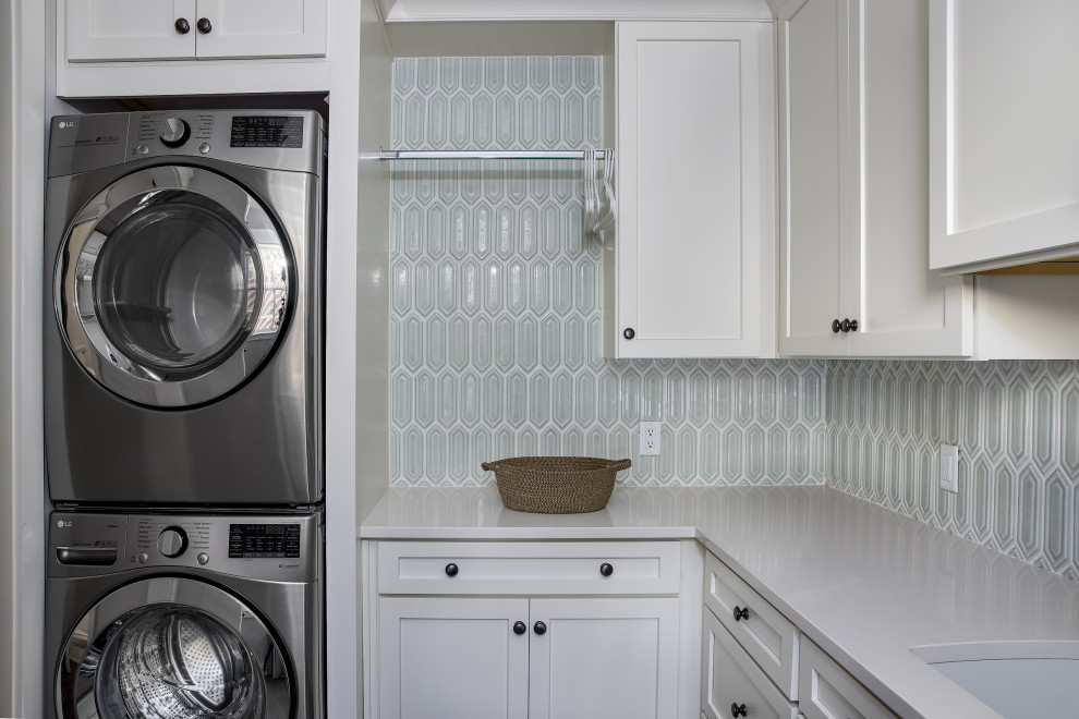 Bild på en vintage vita l-formad vitt tvättstuga enbart för tvätt, med en undermonterad diskho, skåp i shakerstil, vita skåp, bänkskiva i kvarts, grönt stänkskydd och en tvättpelare