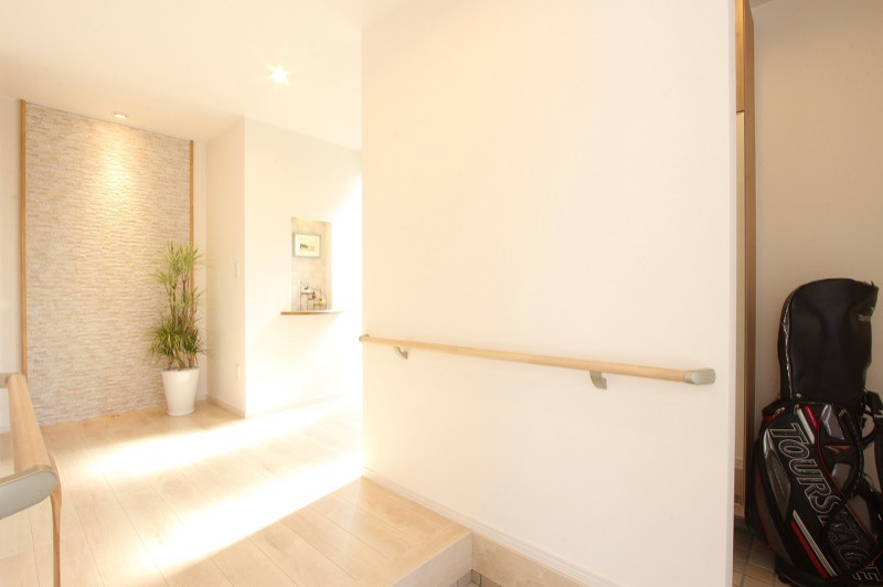 Photo of a mid-sized contemporary entry hall in Fukuoka with white walls, plywood floors, a single front door, a brown front door, beige floor, wallpaper and wallpaper.