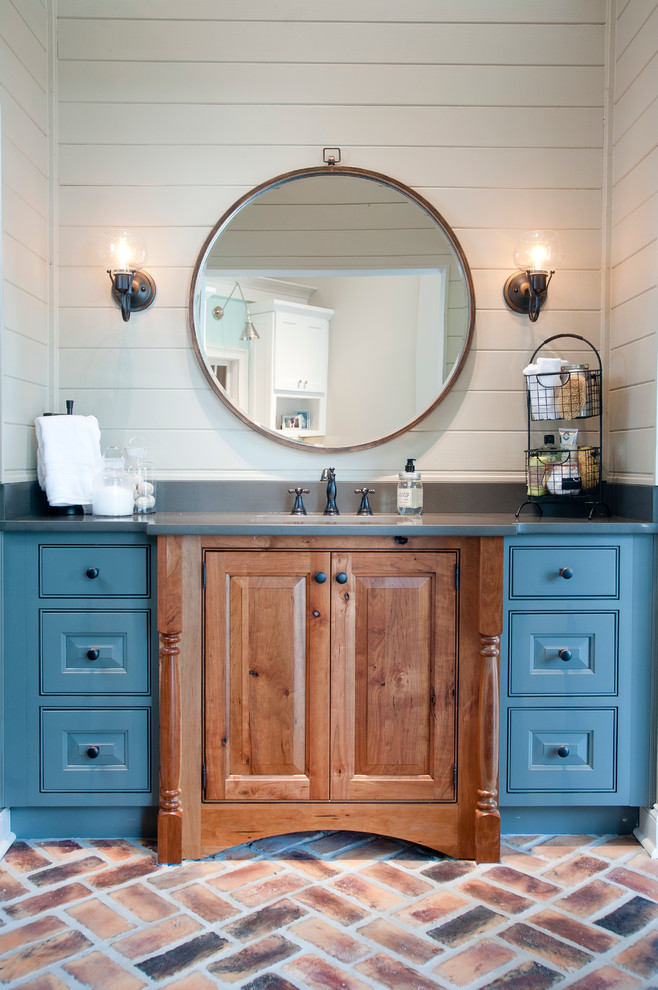 Inspiration for a mid-sized beach style powder room in Atlanta with brick floors, beaded inset cabinets, medium wood cabinets, white tile, white walls, an undermount sink, engineered quartz benchtops, red floor and grey benchtops.