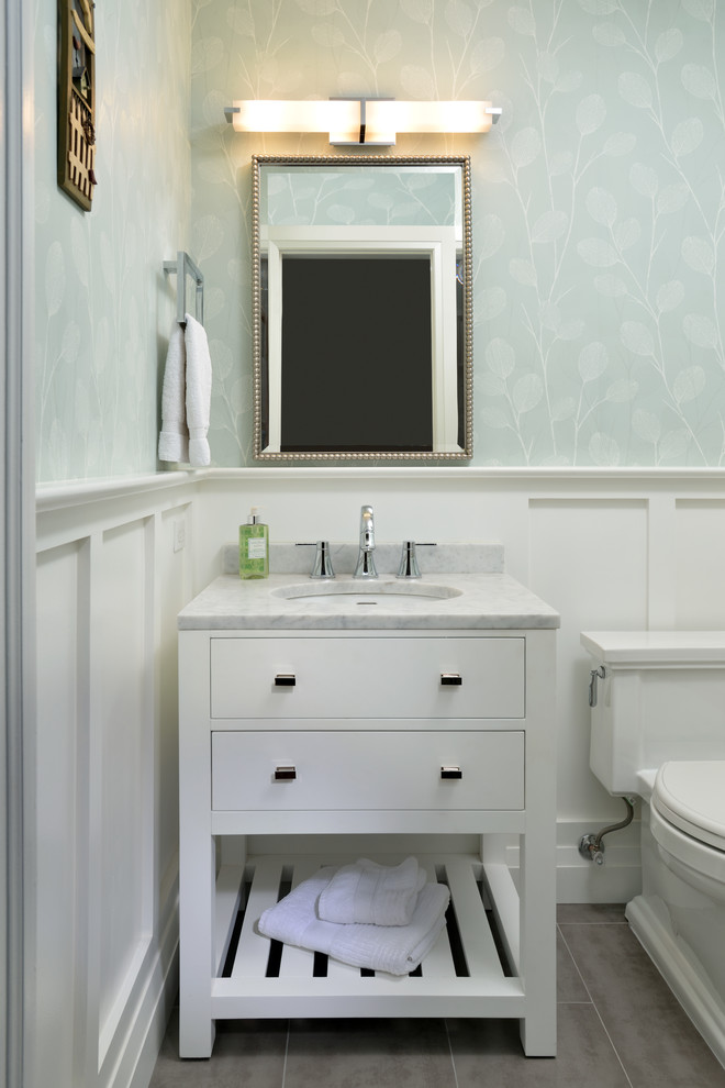 Photo of a transitional powder room in Toronto with white cabinets, a one-piece toilet, porcelain floors, an undermount sink and marble benchtops.