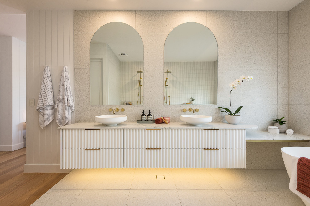 На фото: большая главная ванная комната в современном стиле с отдельно стоящей ванной, бежевой плиткой, полом из керамической плитки, открытым душем, тумбой под две раковины и подвесной тумбой