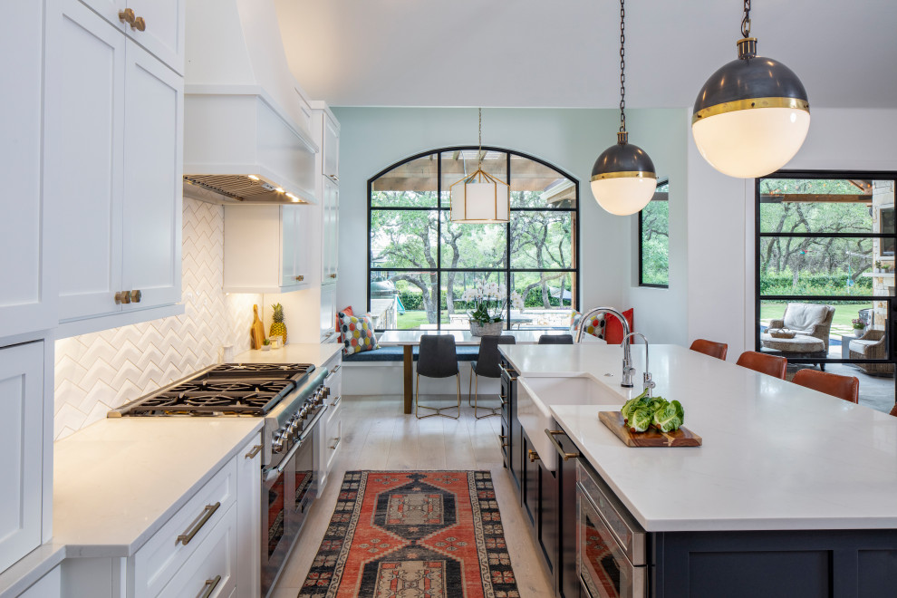 Eat-in kitchen - large transitional u-shaped light wood floor and beige floor eat-in kitchen idea in Austin with a farmhouse sink, recessed-panel cabinets, white cabinets, quartzite countertops, white backsplash, ceramic backsplash, paneled appliances, an island and white countertops