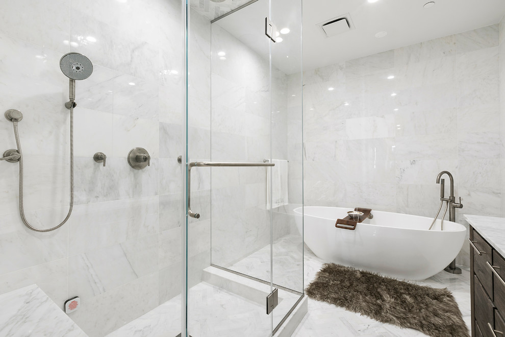 Mid-sized transitional master bathroom in New York with flat-panel cabinets, dark wood cabinets, a freestanding tub, a corner shower, marble, grey walls, marble floors, an undermount sink, marble benchtops, grey floor and a hinged shower door.