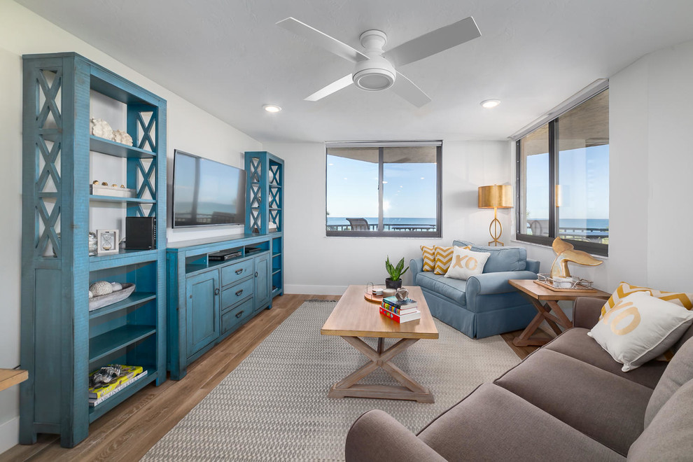 Beach style medium tone wood floor and brown floor family room photo in Tampa with white walls and a wall-mounted tv