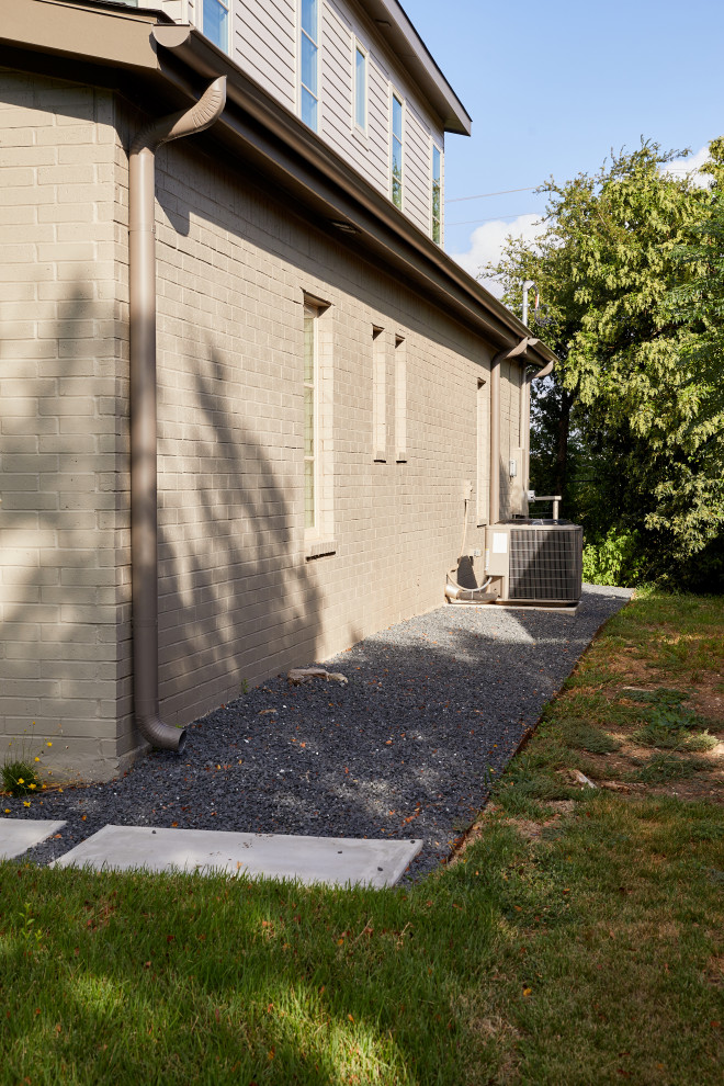 Esempio di un grande vialetto d'ingresso minimal esposto a mezz'ombra davanti casa in estate con un muro di contenimento, pavimentazioni in cemento e recinzione in metallo