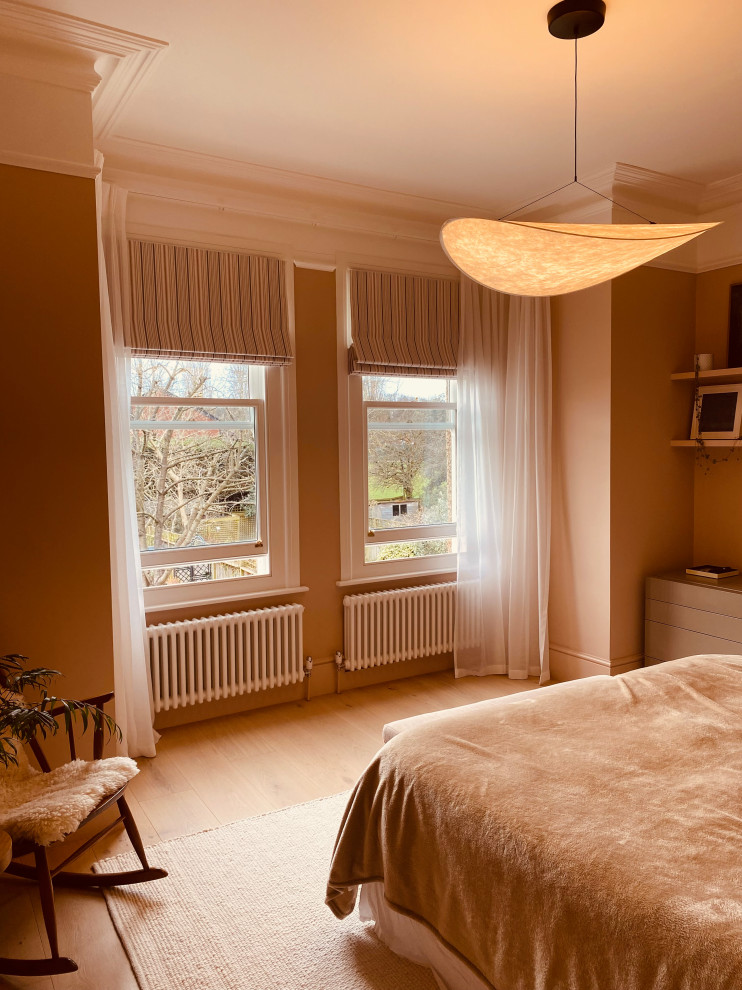 Modelo de dormitorio principal minimalista de tamaño medio con paredes rosas, suelo de madera clara, suelo rosa y madera