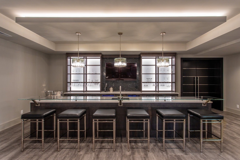Inspiration for a large transitional u-shaped seated home bar in Columbus with an undermount sink, open cabinets, dark wood cabinets, glass benchtops, grey splashback, mosaic tile splashback, light hardwood floors, brown floor and white benchtop.
