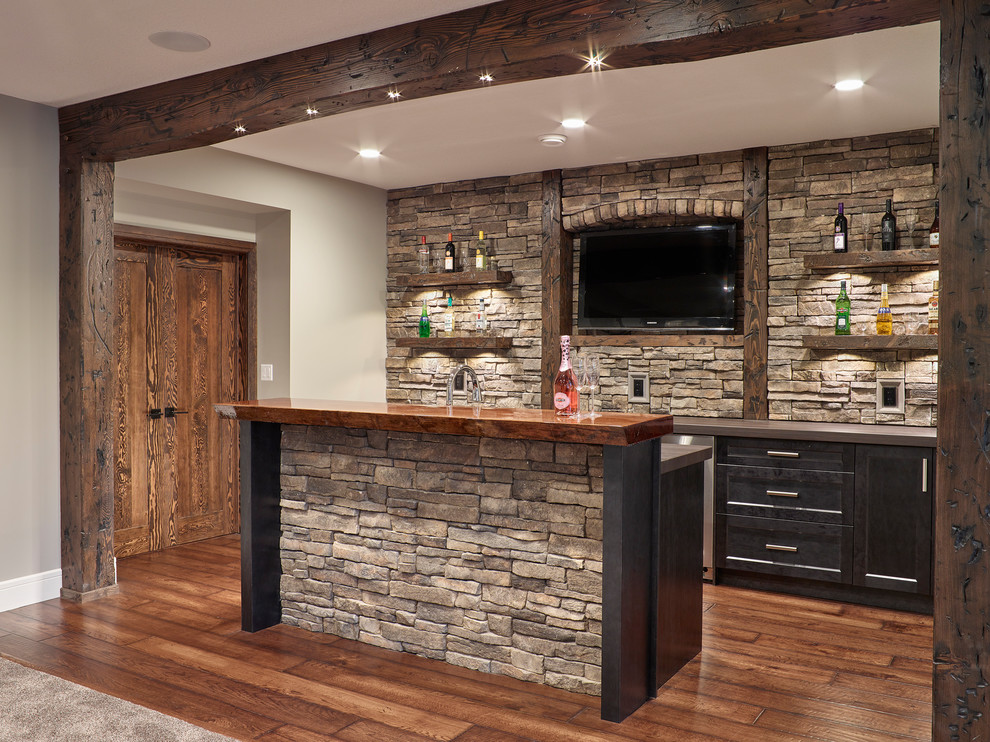 Inspiration for a large arts and crafts galley wet bar in Other with an undermount sink, shaker cabinets, dark wood cabinets, wood benchtops, grey splashback, stone slab splashback, laminate floors, brown floor and brown benchtop.