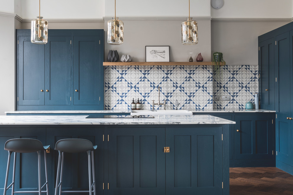 Large contemporary l-shaped eat-in kitchen in Other with a farmhouse sink, shaker cabinets, blue cabinets, marble benchtops, blue splashback, cement tile splashback, stainless steel appliances, dark hardwood floors, with island and brown floor.