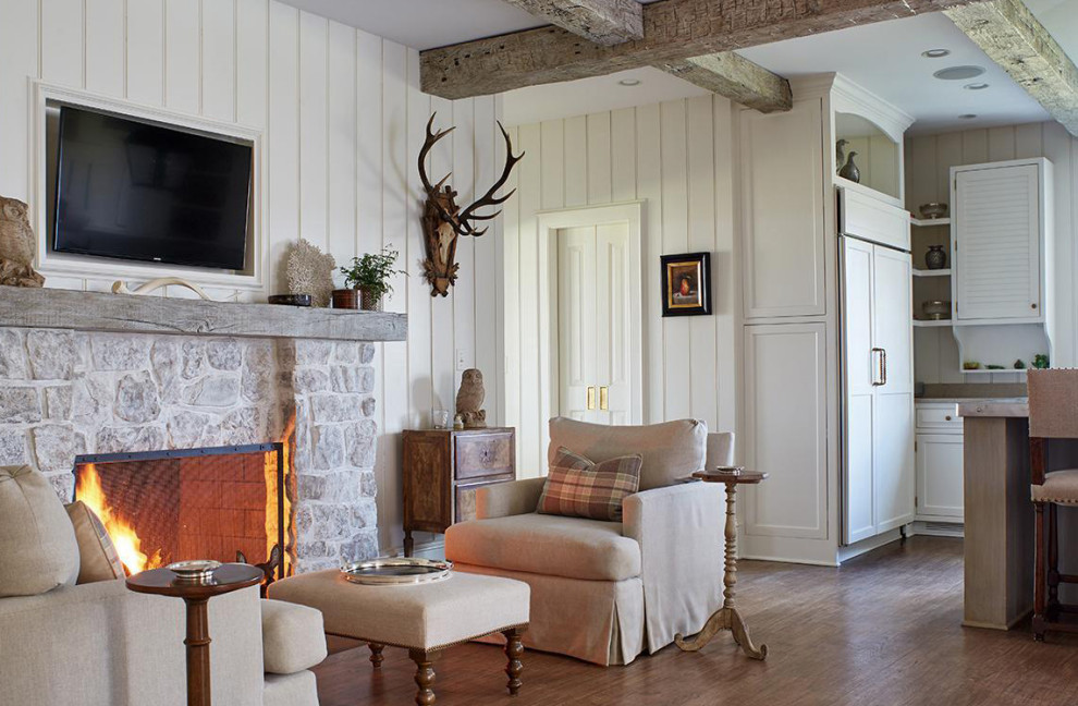 Idée de décoration pour une grande salle de séjour champêtre ouverte avec un mur beige, un sol en bois brun, une cheminée standard, un manteau de cheminée en pierre et un téléviseur fixé au mur.