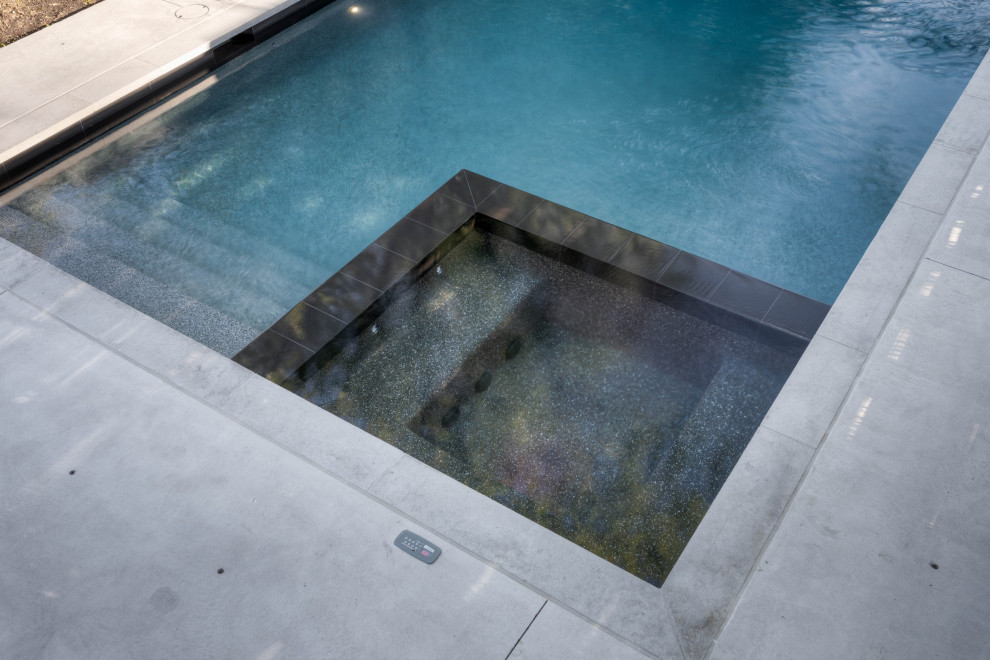 This is an example of a small classic back rectangular hot tub in Toronto with stamped concrete.