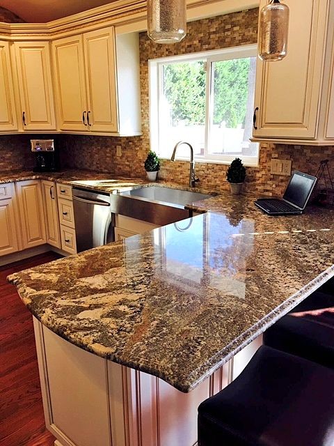 Mid-sized transitional u-shaped dark wood floor open concept kitchen photo in New York with a farmhouse sink, raised-panel cabinets, white cabinets, granite countertops, brown backsplash, stone tile backsplash and stainless steel appliances