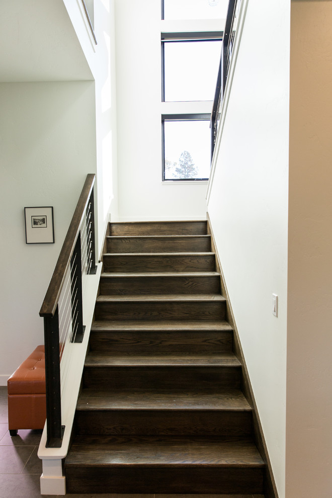 Photo of a large transitional wood u-shaped staircase in Other with wood risers and cable railing.
