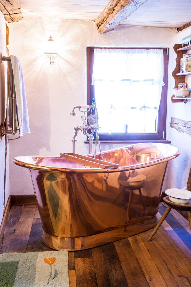 This is an example of a country 3/4 bathroom in Munich with a freestanding tub, a curbless shower, a wall-mount toilet, white walls, dark hardwood floors, a vessel sink, wood benchtops, brown floor and a sliding shower screen.