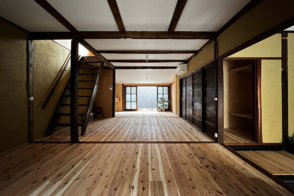 Small open concept family room in Kyoto with brown walls, light hardwood floors, brown floor and exposed beam.