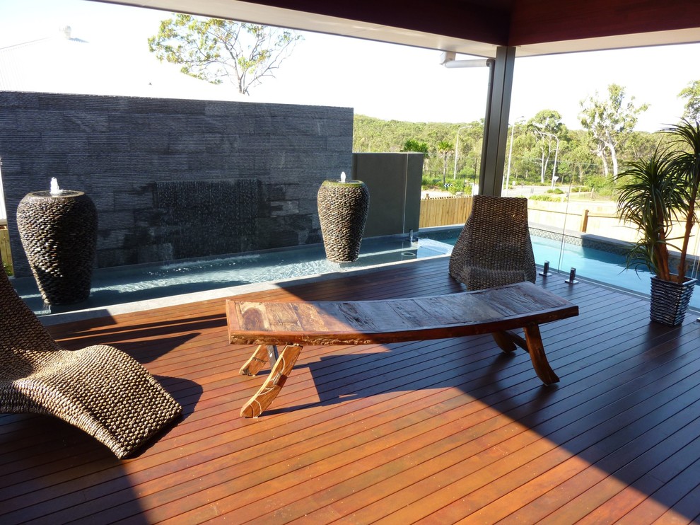 Mid-sized asian backyard deck in Sunshine Coast with a water feature and a roof extension.