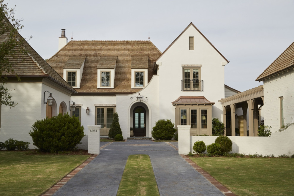 This is an example of a large two-storey brick white house exterior in New Orleans with a shingle roof.