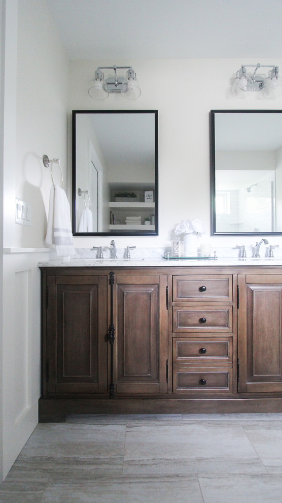 Inspiration for a mid-sized country master bathroom in Minneapolis with brown cabinets, a double shower, a two-piece toilet, white tile, subway tile, white walls, vinyl floors, an undermount sink, marble benchtops, grey floor, a hinged shower door and white benchtops.