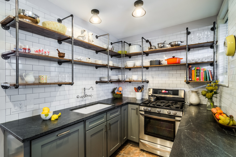 Design ideas for a small industrial l-shaped kitchen in Boston with an undermount sink, shaker cabinets, grey cabinets, granite benchtops, white splashback, subway tile splashback, no island, stainless steel appliances, slate floors and brown floor.