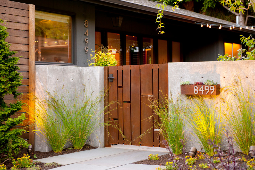 This is an example of a small midcentury front yard partial sun garden in Seattle with a garden path and natural stone pavers.
