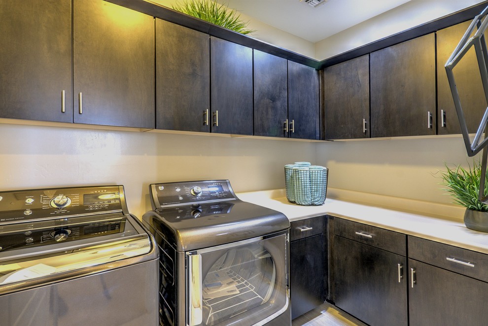 This is an example of a mid-sized modern l-shaped utility room in Phoenix with flat-panel cabinets, dark wood cabinets, laminate benchtops, beige walls, porcelain floors and a side-by-side washer and dryer.