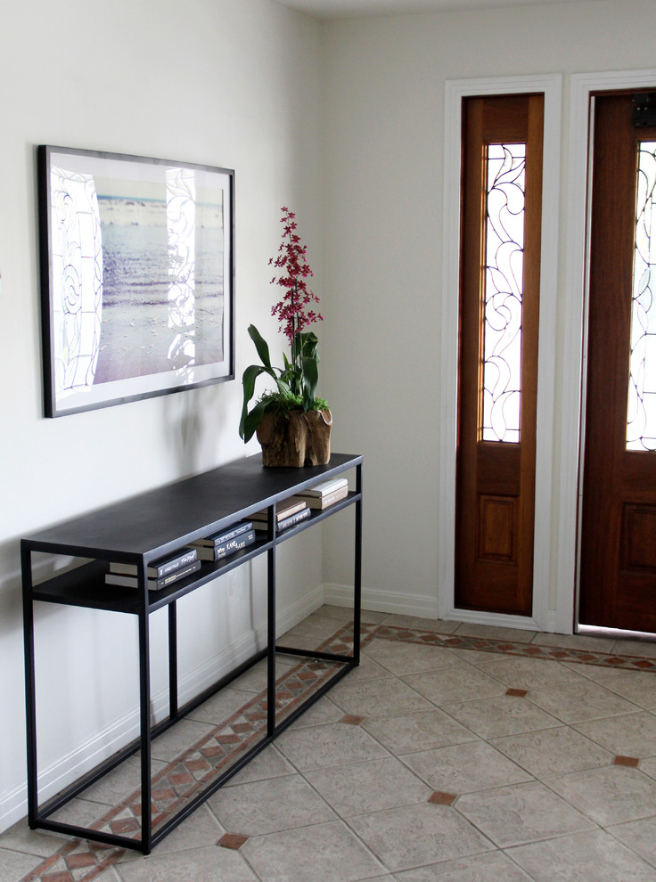 Photo of a small transitional entryway in Los Angeles with white walls, ceramic floors, a single front door and a medium wood front door.