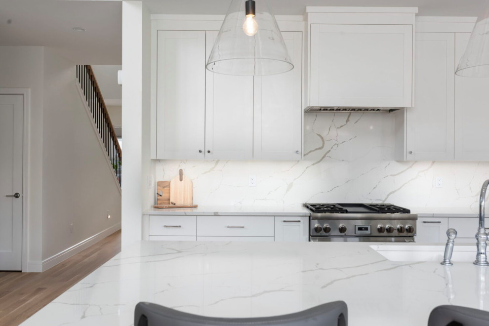 Inspiration for a large transitional l-shaped medium tone wood floor, brown floor and coffered ceiling open concept kitchen remodel in Austin with beaded inset cabinets, white cabinets, quartz countertops, white backsplash, quartz backsplash, stainless steel appliances, an island, white countertops and an undermount sink
