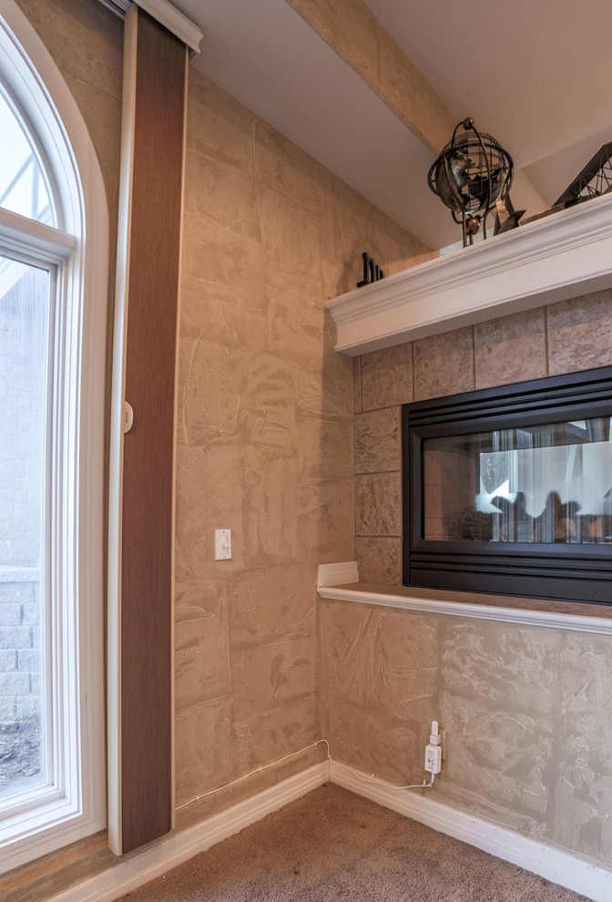 Example of a large classic enclosed carpeted home design design in Omaha with beige walls, a two-sided fireplace and a media wall