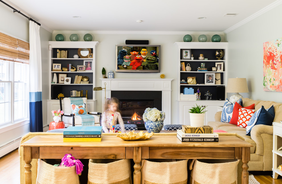 Example of a classic light wood floor living room design in Boston with white walls, a standard fireplace and a wall-mounted tv