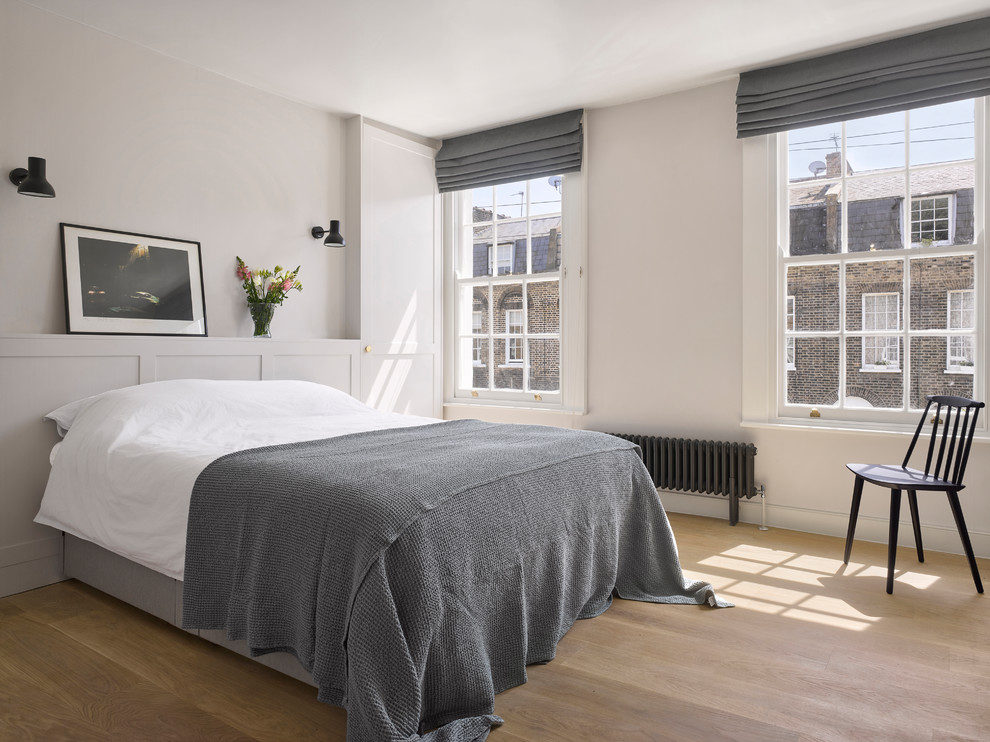 This is an example of a contemporary bedroom in London with white walls, light hardwood floors and beige floor.