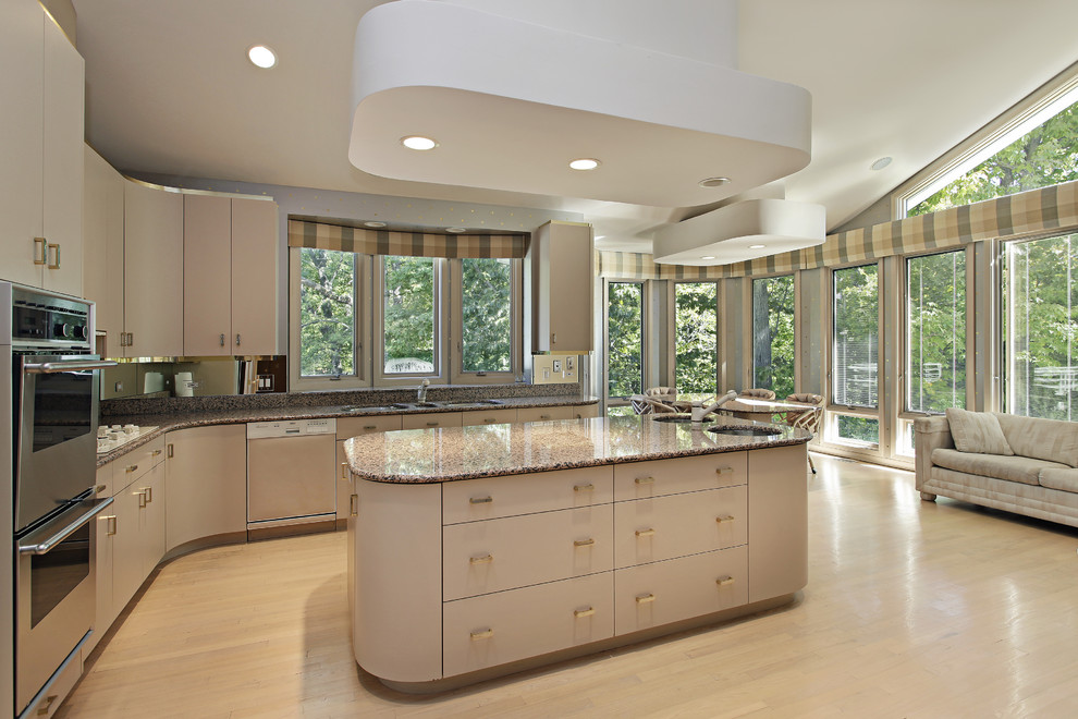 Large trendy l-shaped light wood floor and beige floor open concept kitchen photo with a triple-bowl sink, flat-panel cabinets, beige cabinets, granite countertops, stainless steel appliances and an island