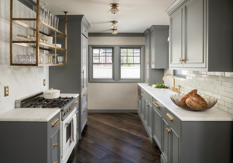 Traditional galley kitchen in Salt Lake City with a single-bowl sink, recessed-panel cabinets, grey cabinets, white splashback, subway tile splashback, panelled appliances, dark hardwood floors, no island, brown floor and white benchtop.