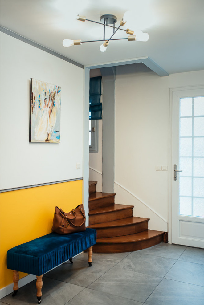 На фото: фойе среднего размера в стиле неоклассика (современная классика) с желтыми стенами, полом из керамической плитки, белой входной дверью, серым полом и панелями на стенах с
