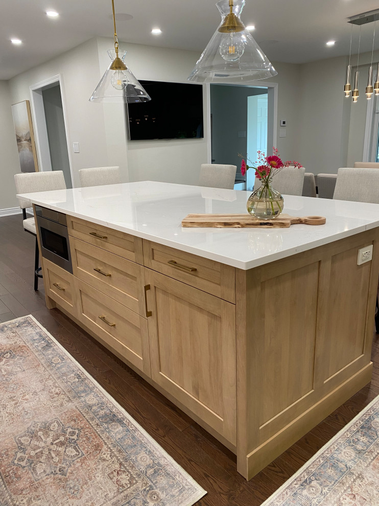 Inspiration for a mid-sized transitional l-shaped medium tone wood floor and brown floor eat-in kitchen remodel in Toronto with an undermount sink, shaker cabinets, white cabinets, quartz countertops, white backsplash, quartz backsplash, stainless steel appliances, an island and white countertops