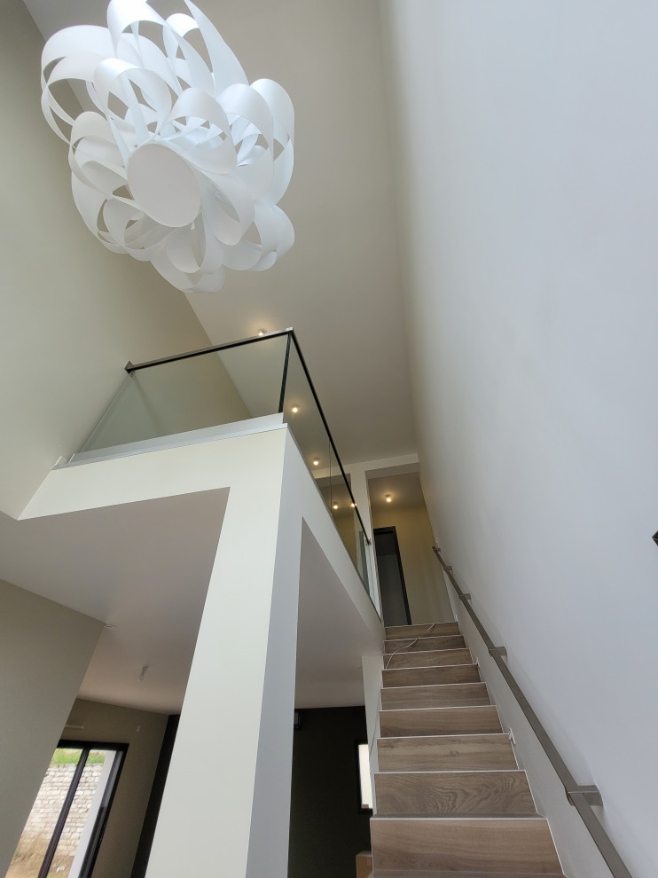 Photo of a large modern concrete straight staircase in Paris with concrete risers and glass railing.