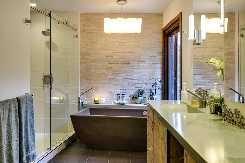 Design ideas for a large contemporary master bathroom in Other with flat-panel cabinets, light wood cabinets, a freestanding tub, an alcove shower, a one-piece toilet, green tile, glass sheet wall, beige walls, porcelain floors, an integrated sink and concrete benchtops.