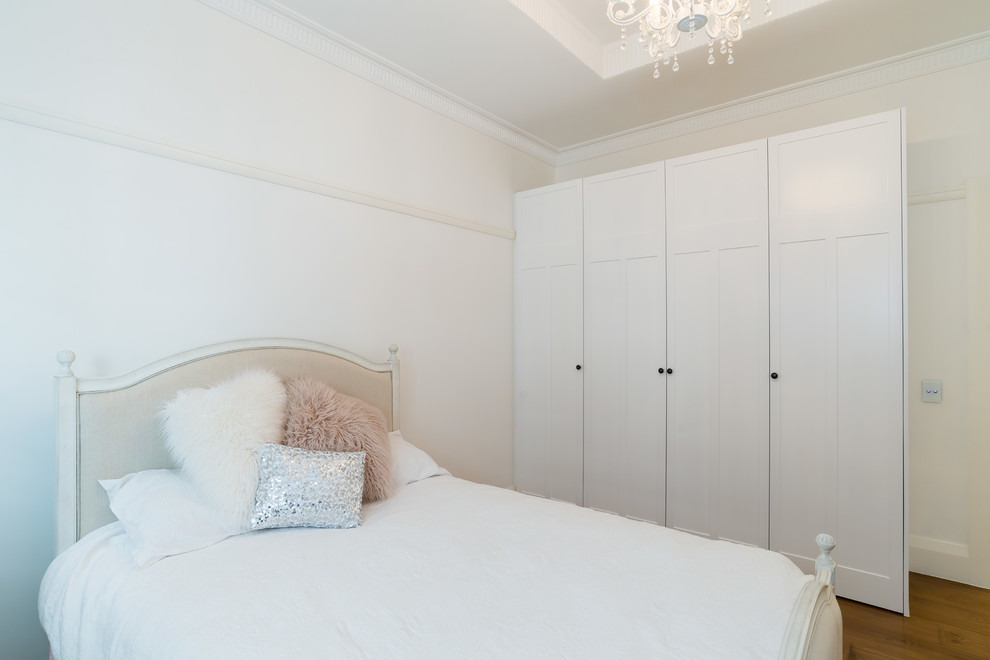 Photo of a large traditional guest bedroom in Sydney with white walls, light hardwood floors and brown floor.