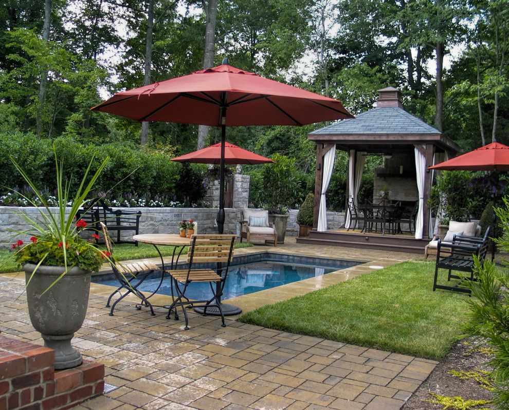 This is an example of a small traditional backyard rectangular aboveground pool in Charlotte with a pool house and natural stone pavers.