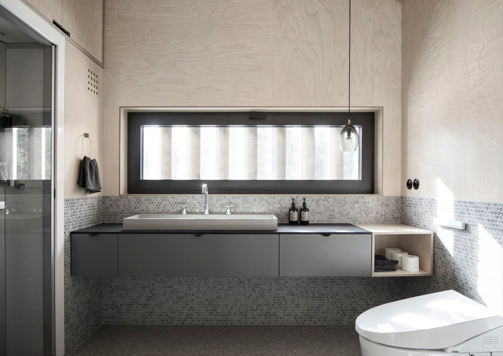 This is an example of a small scandinavian bathroom in Saint Petersburg with flat-panel cabinets, grey cabinets, gray tile, mosaic tile, mosaic tile floors, engineered quartz benchtops, grey floor, a wall-mount toilet and a vessel sink.