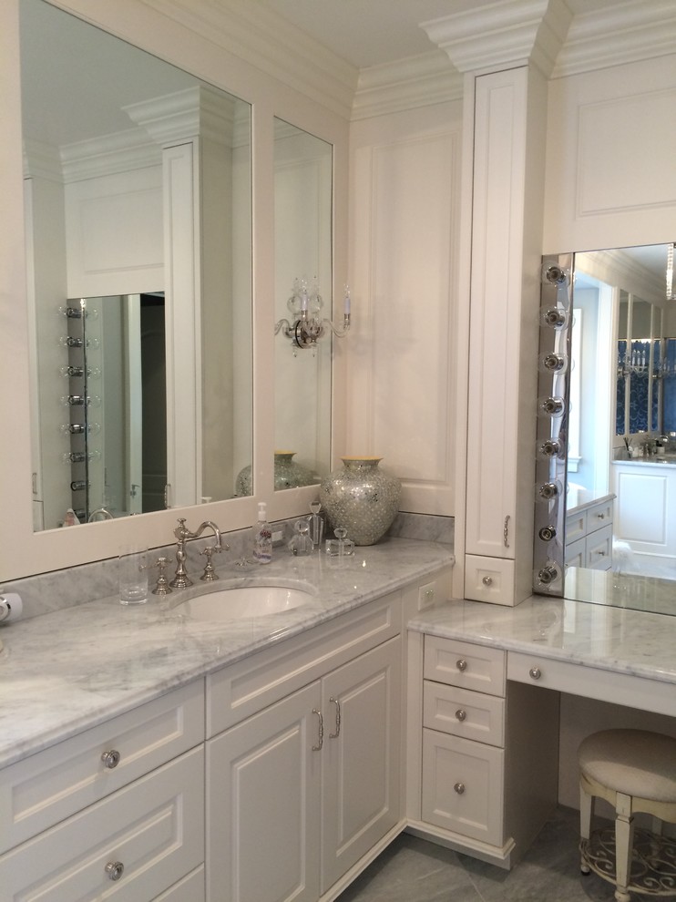Example of a large transitional master marble floor drop-in bathtub design in Cleveland with raised-panel cabinets, white cabinets, a two-piece toilet, blue walls, an undermount sink, marble countertops and white countertops