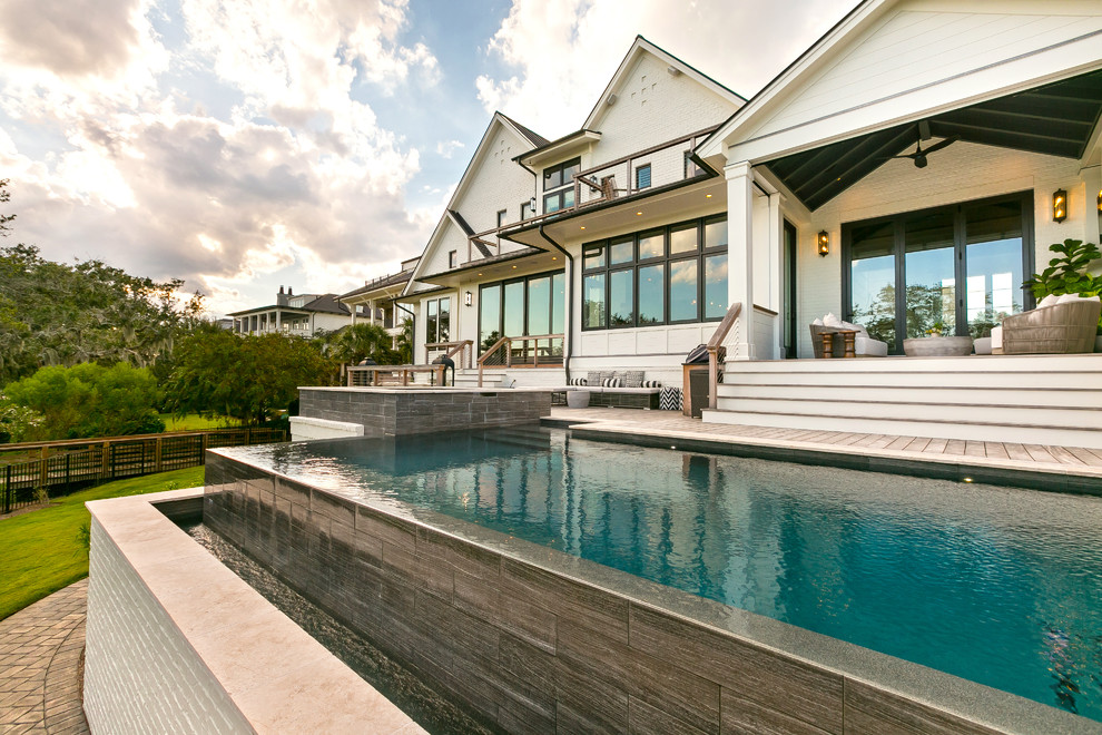 Inspiration for a large transitional backyard rectangular infinity pool in Charleston with a hot tub and decking.