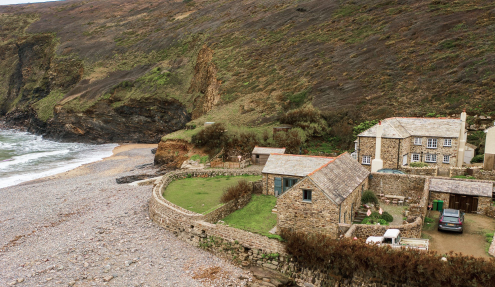 Cette photo montre une façade de maison bord de mer en pierre de taille moyenne et à niveaux décalés avec un toit à deux pans et un toit en tuile.