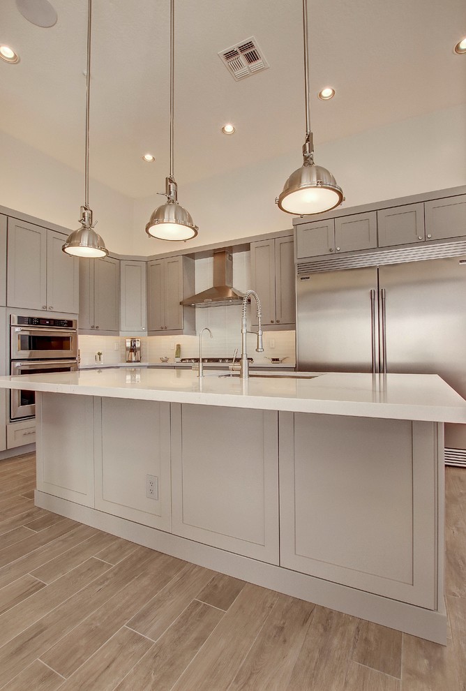 Eat-in kitchen - large transitional l-shaped porcelain tile and brown floor eat-in kitchen idea in Phoenix with an undermount sink, shaker cabinets, gray cabinets, quartz countertops, white backsplash, subway tile backsplash, stainless steel appliances, an island and white countertops