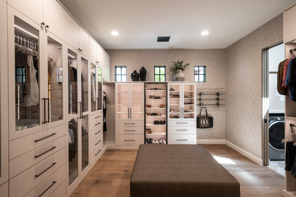 Walk-in closet - large contemporary gender-neutral medium tone wood floor and brown floor walk-in closet idea in Phoenix with glass-front cabinets and white cabinets