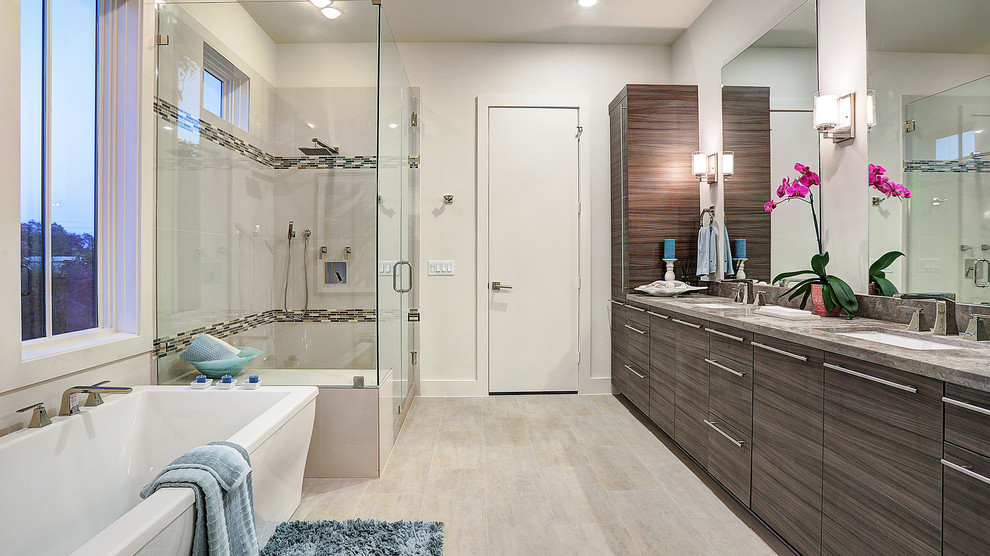 This is an example of a contemporary bathroom in Houston with flat-panel cabinets, dark wood cabinets, a freestanding tub, a corner shower, gray tile, white walls, an undermount sink and grey benchtops.