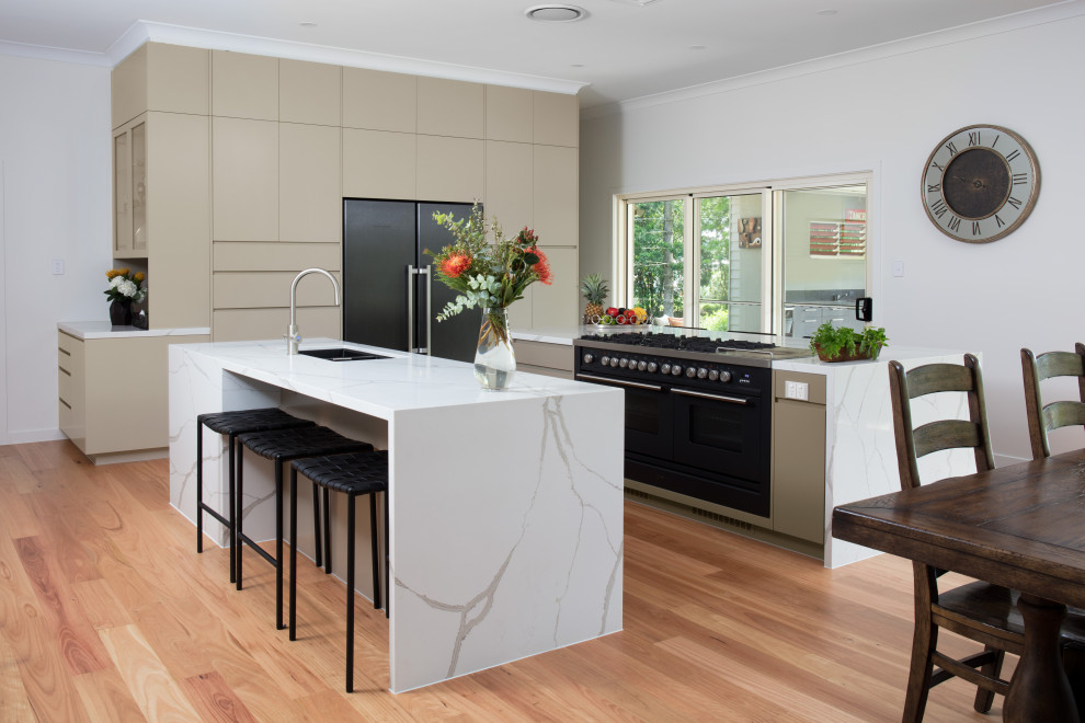 Photo of an expansive contemporary galley eat-in kitchen in Brisbane with an undermount sink, beige cabinets, quartz benchtops, stainless steel appliances, light hardwood floors, multiple islands and white benchtop.