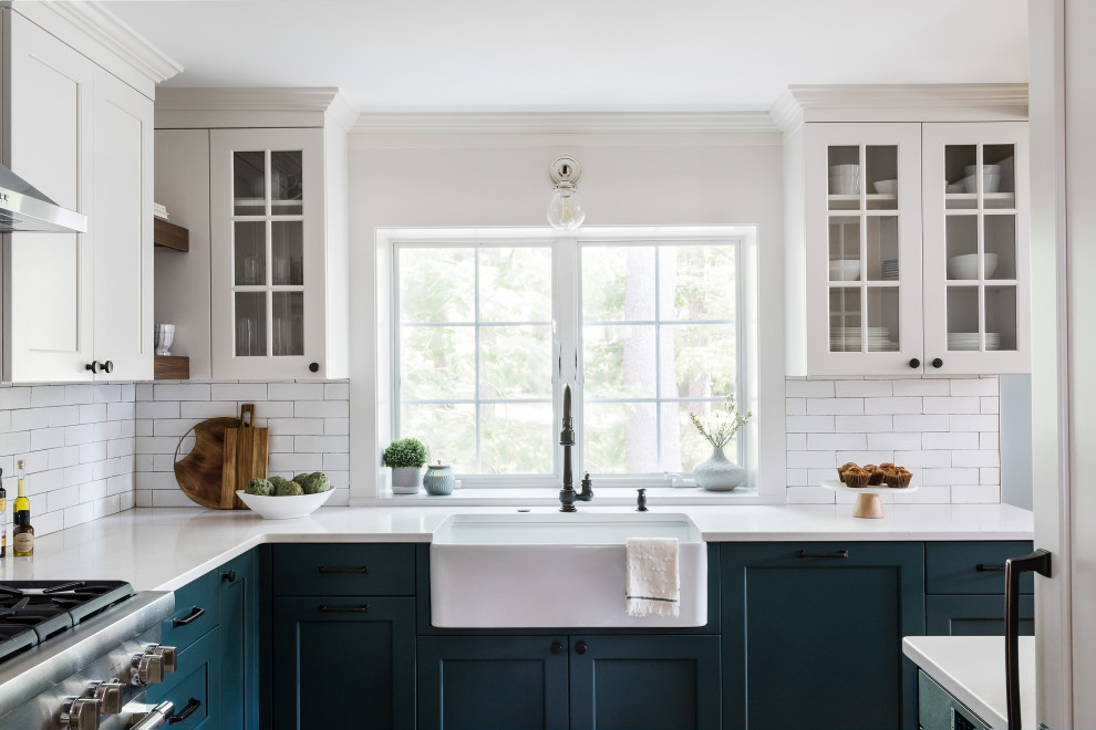 This is an example of a mid-sized country l-shaped kitchen pantry in Boston with a farmhouse sink, shaker cabinets, blue cabinets, quartz benchtops, white splashback, subway tile splashback, stainless steel appliances, medium hardwood floors, no island, brown floor and blue benchtop.