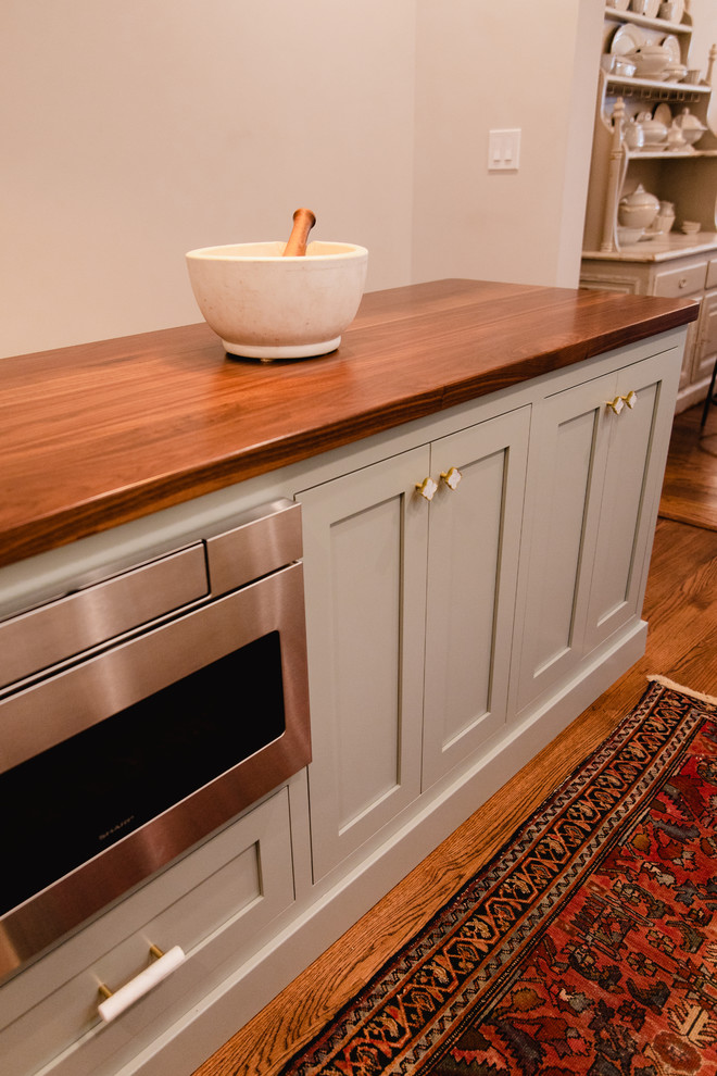 Small transitional l-shaped dark wood floor and brown floor eat-in kitchen photo in Baltimore with a farmhouse sink, shaker cabinets, white cabinets, quartz countertops, white backsplash, cement tile backsplash, stainless steel appliances, an island and white countertops